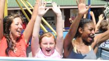 Three female friends with their hands in the air on a spinning thrill ride at The Great Escape.