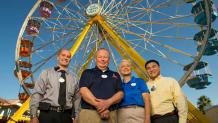 Six Flags employees standing in front of a ferris wheel ride