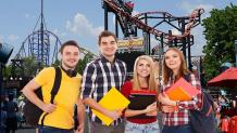 teens holding notebooks and standing in front of a coaster