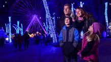 family standing outside observing holiday lights