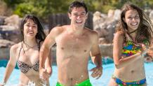Young adults running into the wave pool smiling.