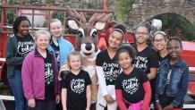 group of girls standing with a reindeer character
