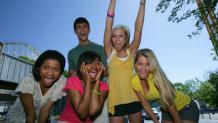 excited teenagers cheering with a little bit of a coaster behind them