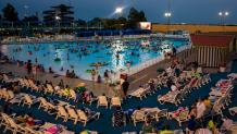 Guests watch a movie on a big screen while lounging in the wave pool