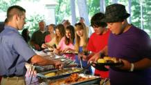 group of people getting food in a buffet line