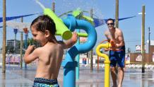 A young child and father play in the water.