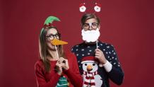 Couple having fun with props while wearing ugly holiday sweaters