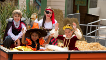 4 children sitting on a hay ride in Halloween costumes