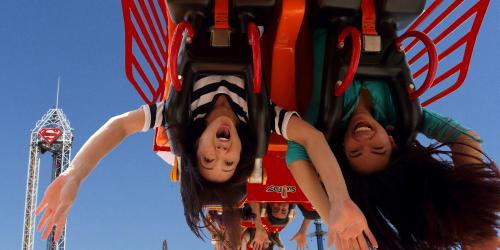 two girls with their hands up while on a coaster