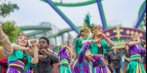 Group of Dancers and Guests dancing together with their arms in the air on the midway of the park