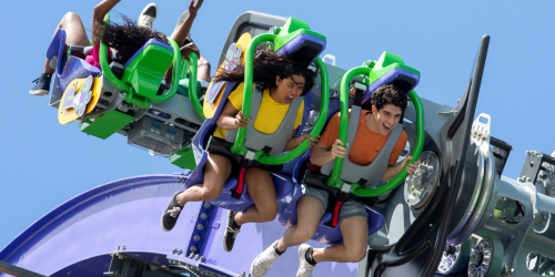 Two people on the top of THE JOKER Free Fly Coaster riding and screaming.