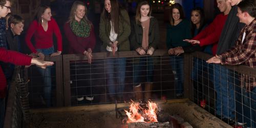 Guests standing around camp fire