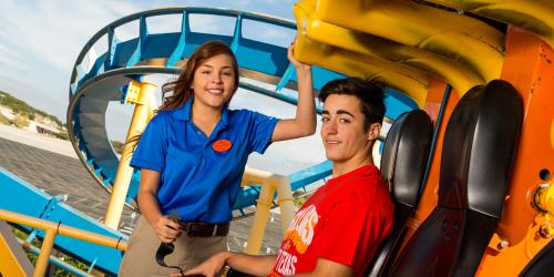 Employee helping guest onto rollercoaster