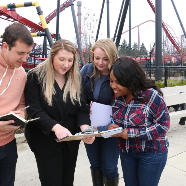 Students in front of Rollercoaster with teacher and clipboards