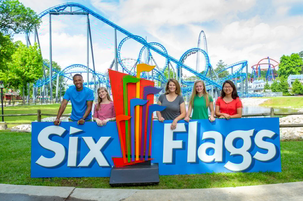 group posing for picture at six flags sign